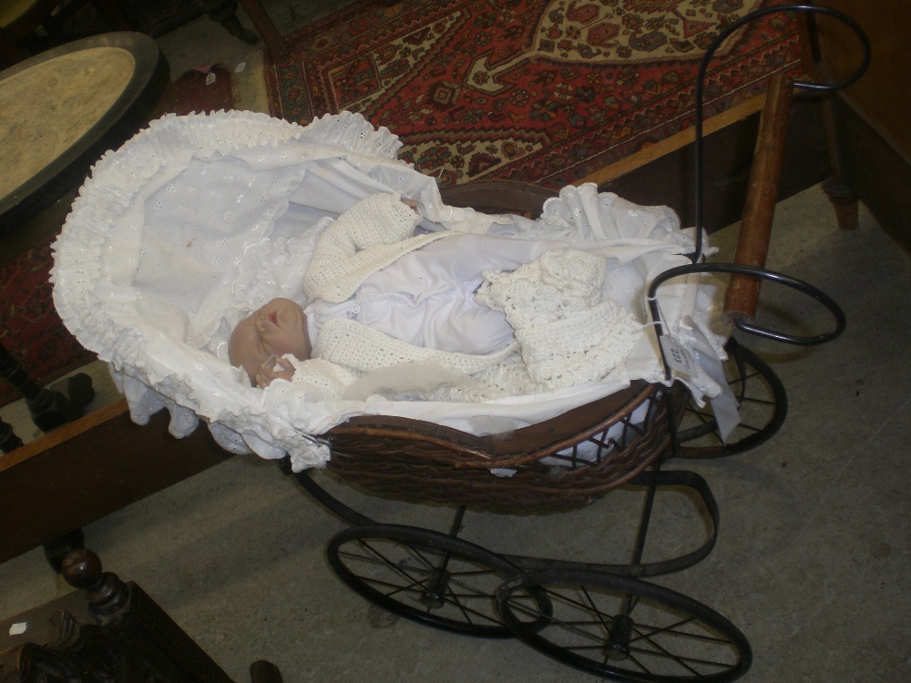 A newborn baby type doll in vintage style pram