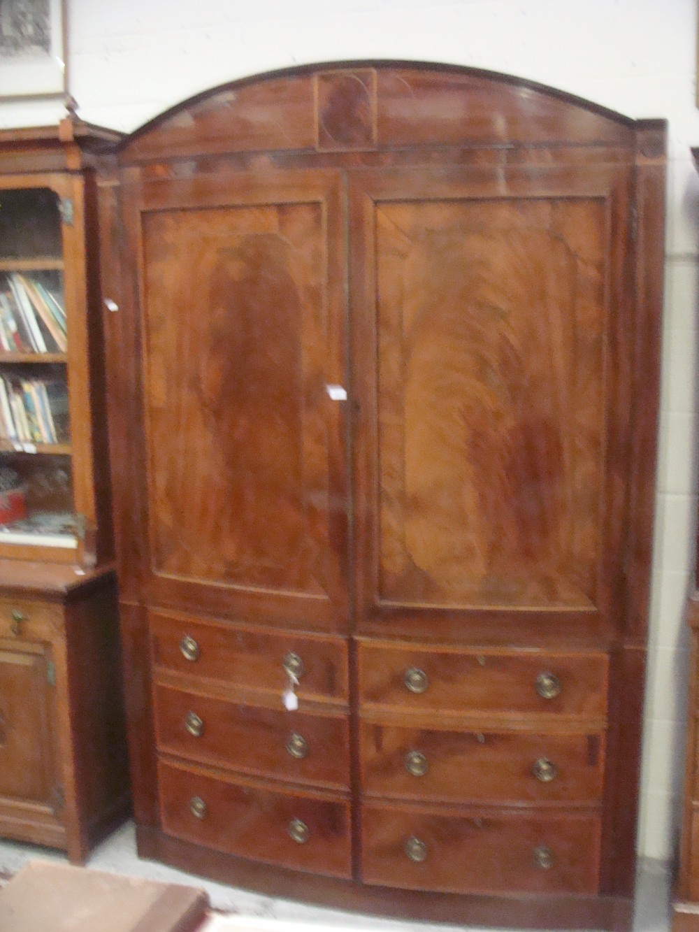 A George III mahogany bowfront linen press, the doors with crossbanded panels over six dummy