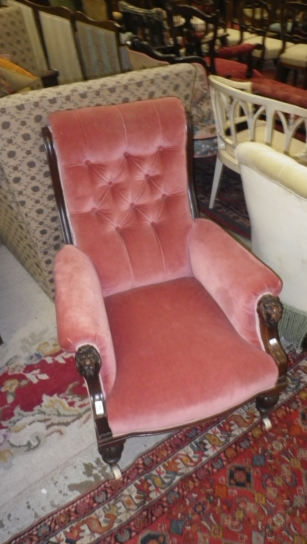 A late Victorian mahogany open armchair with carved lion mask arm terminals with pink velvet