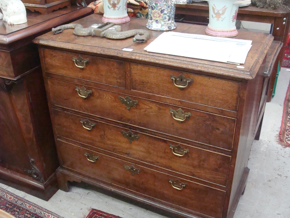 A George III oak chest of drawers with brass drop handles on bracket feet