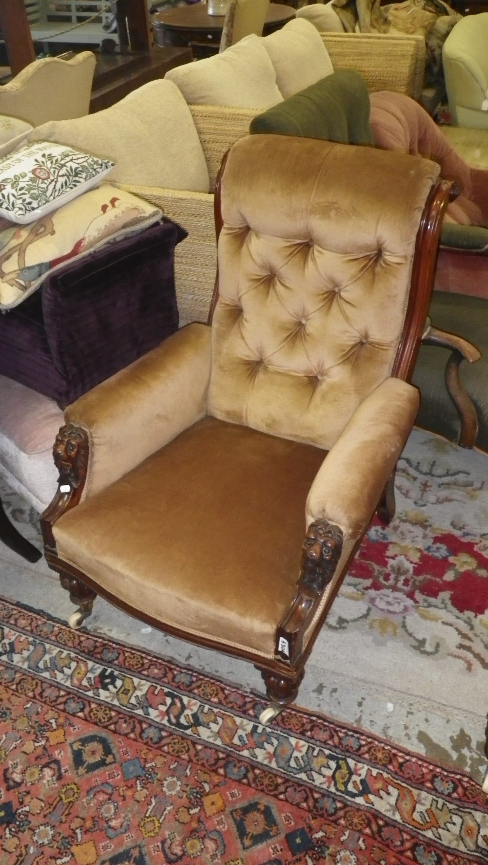 A late Victorian mahogany open armchair with carved lion mask arm terminals with brown velvet