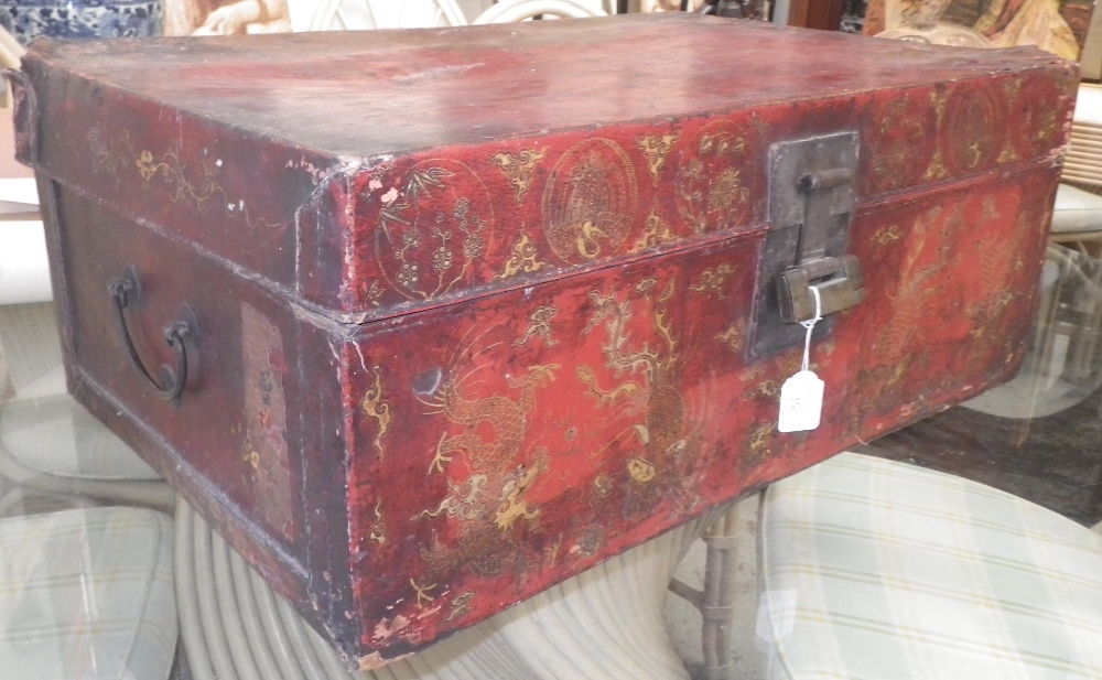 An Oriental red lacquer covered fabric trunk with gilt decoration