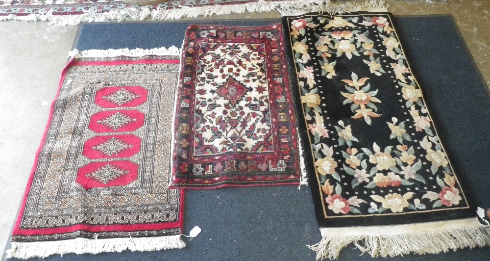 A Persian design red ground rug and two similar rugs.
