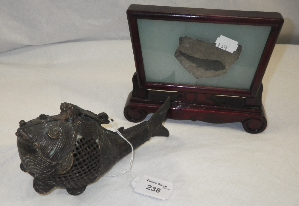 An Oriental wirework model of a fish and a cased fossilized fish.