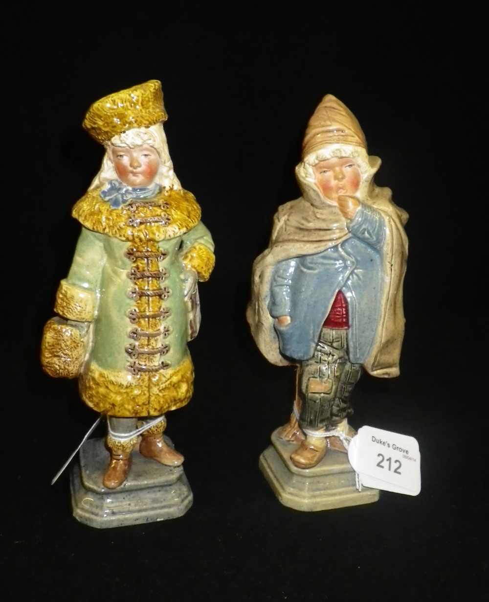 Two Continental ceramic ornaments of a boy and girl in winter clothing.