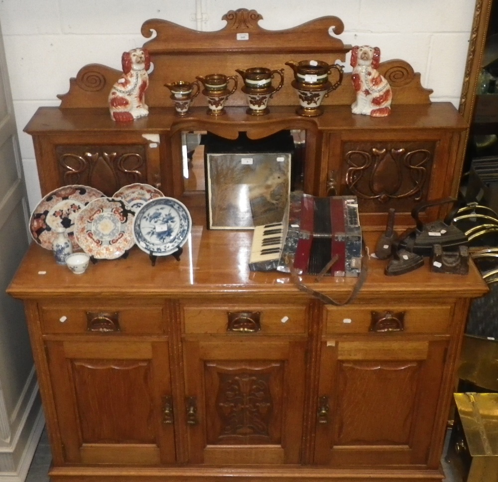 An Arts and Crafts golden oak sideboard with inset hand beaten copper panels and similar copper drop