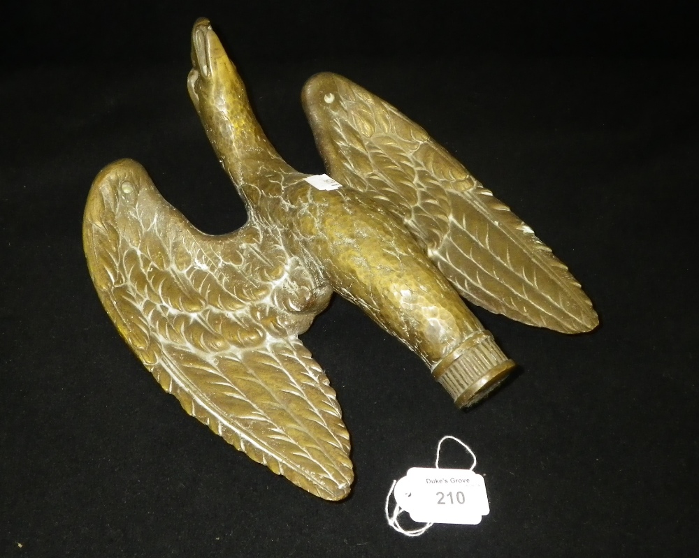 A cast metal sculpture in the form of a winged bird with open beak.