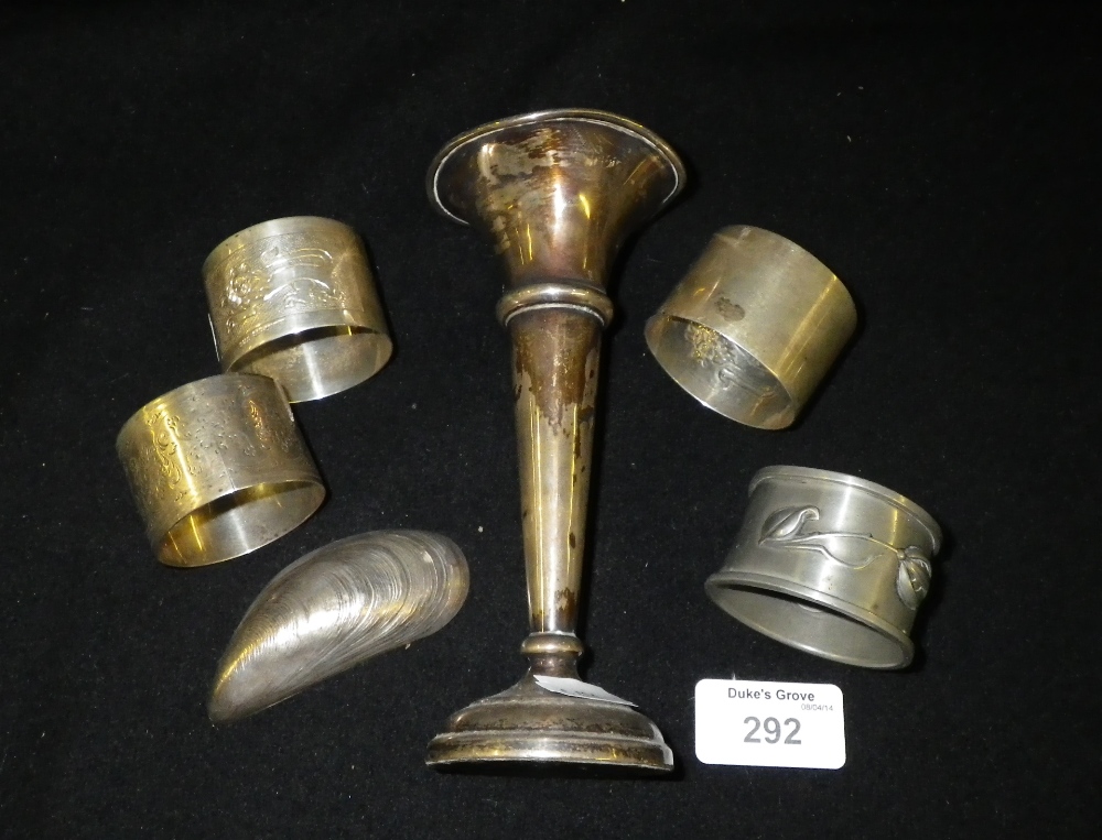 A loaded silver posy vase, three silver napkin rings and other metalware items.