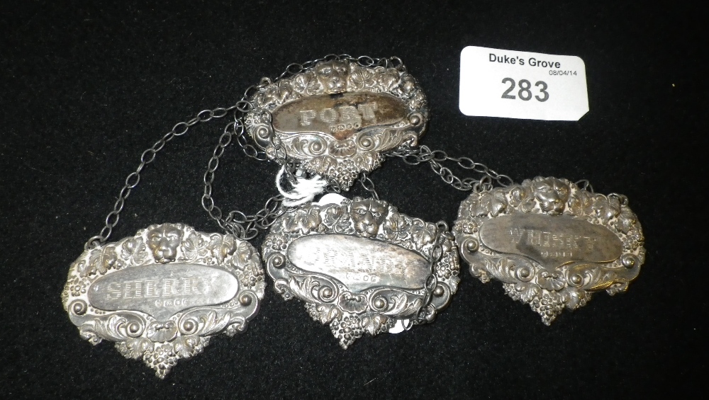 A set of four London silver spirit labels with lion`s head and vine motifs for Port, Sherry, Whiskey