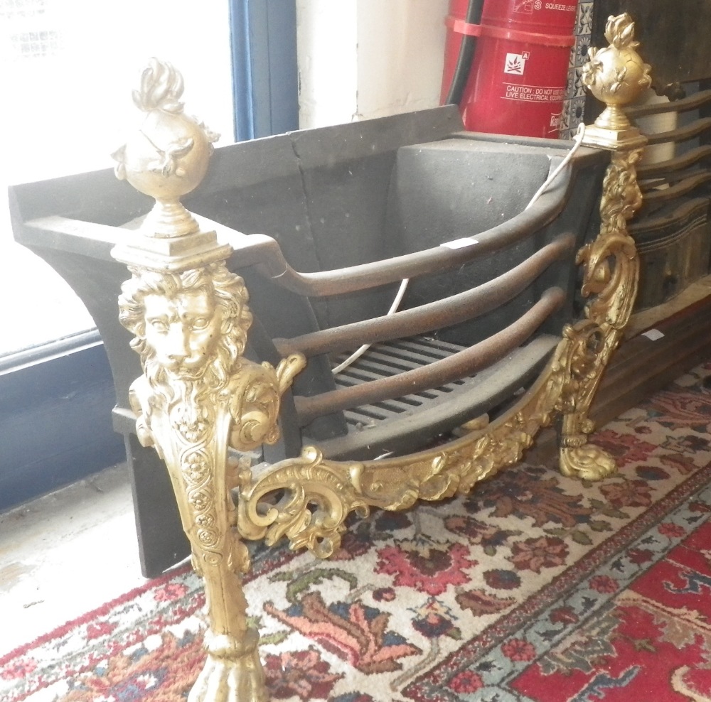 A 19th century cast-iron and gilt hob grate, with rococo style gilded front decorated with lion mask