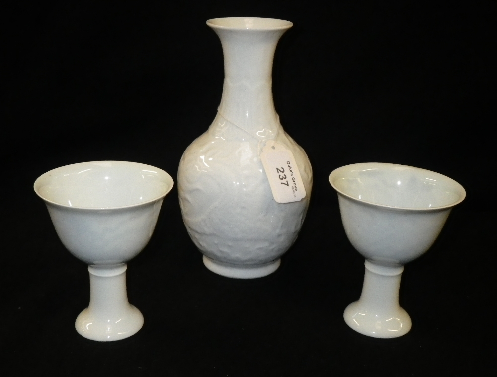 A Chinese Anhua style garniture, consisting of a baluster vase and two stem cups.