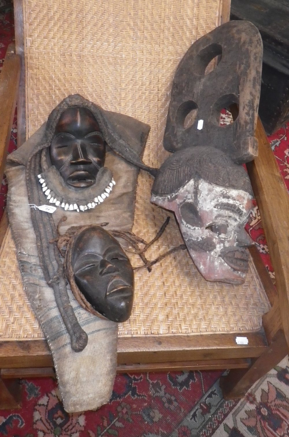 An African tribal mask decorated with teeth, another similar and a larger wooden tribal mask with