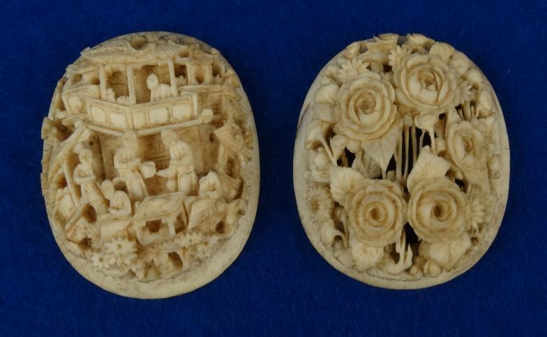 Two oval Chinese Canton ivory panels - one carved in relief with a view of figures amongst