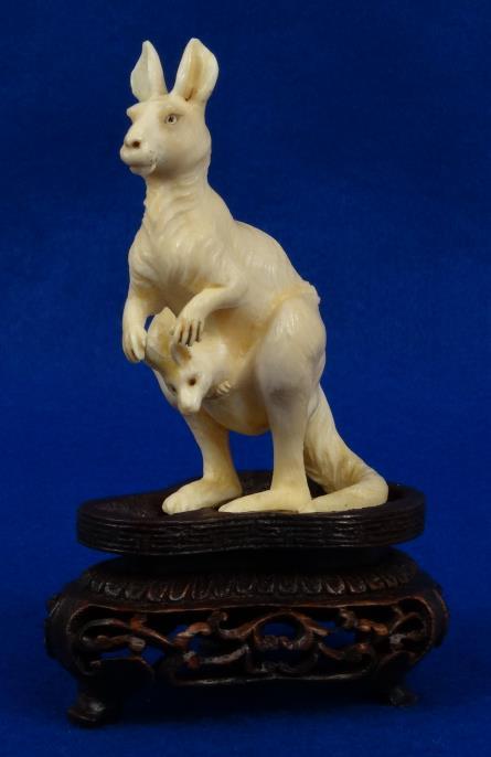 Oriental carved ivory coloured composition kangaroo and joey study raised on a wood stand, 11cm