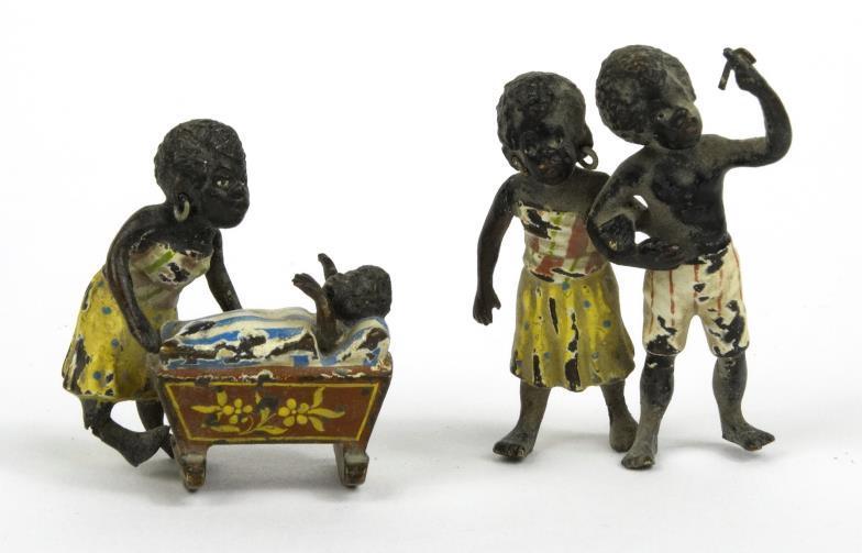 Hand painted miniature bronze African boy and girl, together with a baby in a pram, the largest 3.