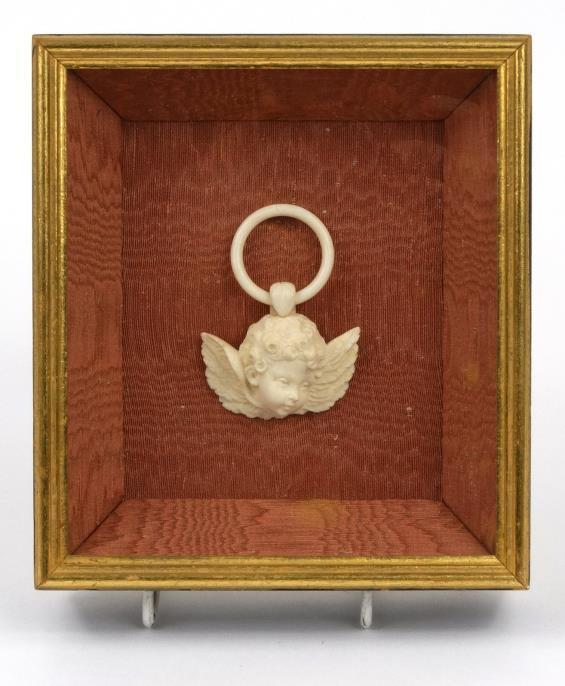 Antique carved ivory cherub head suspension loop housed in a box frame, the frame 19cm x 17cm : For