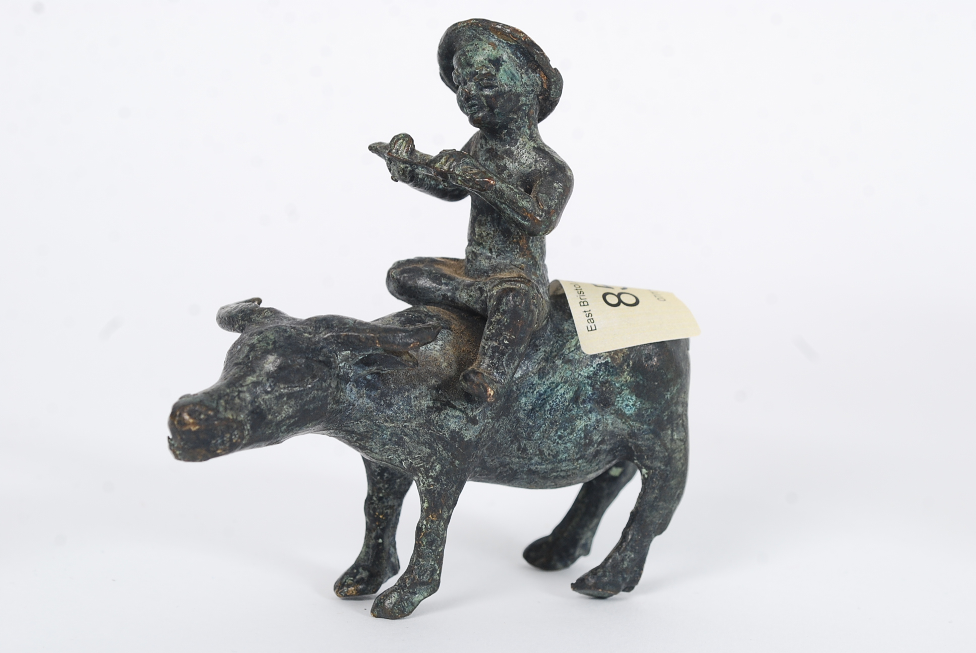 A 19th century bronze figure of a boy riding a cow. Chinese. 11cm tall.