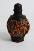 A Chinese carved walnut snuff bottle complete with stopper being raised on circular base