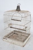 A large early 20th century painted wirework bird cage of square form having set perch within and