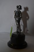 A tested silver figurine of a fly fisherman being raised on naturalistic plinth and set on an