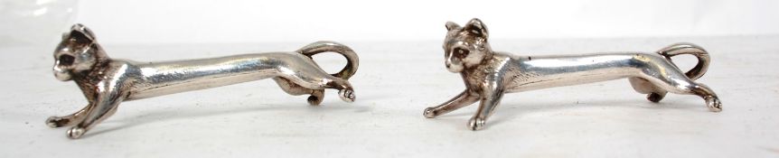 A pair of white metal silver knife rests in the form of cats