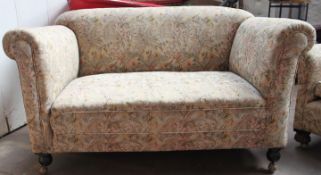 A 1930`s Chesterfield drop arm cottage sofa settee couch being raised on bun feet with castors