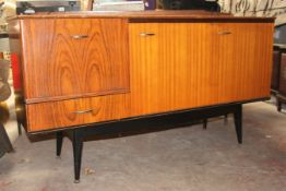 A retro 1970`s teak sideboard of small proportions being raised on ebonised turned legs with