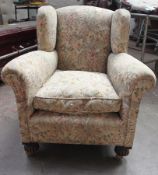 A 1930`s Chesterfield cottage armchair being raised on bun feet with castors having tapestry