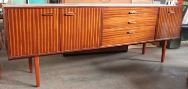 A retro 1970`s teak sideboard of large  proportions being raised on turned legs with a double door