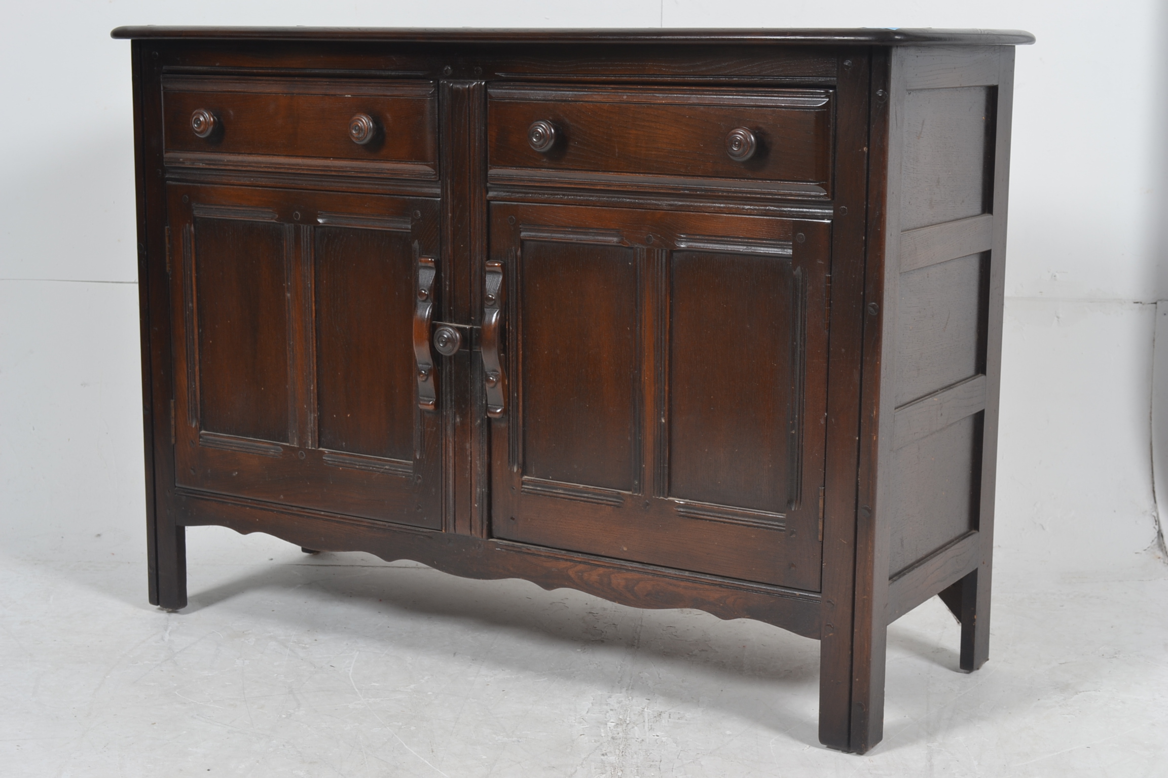 An Ercol beech and elm Jacobean style sideboard having 2 short drawers over 2 cupboards with a