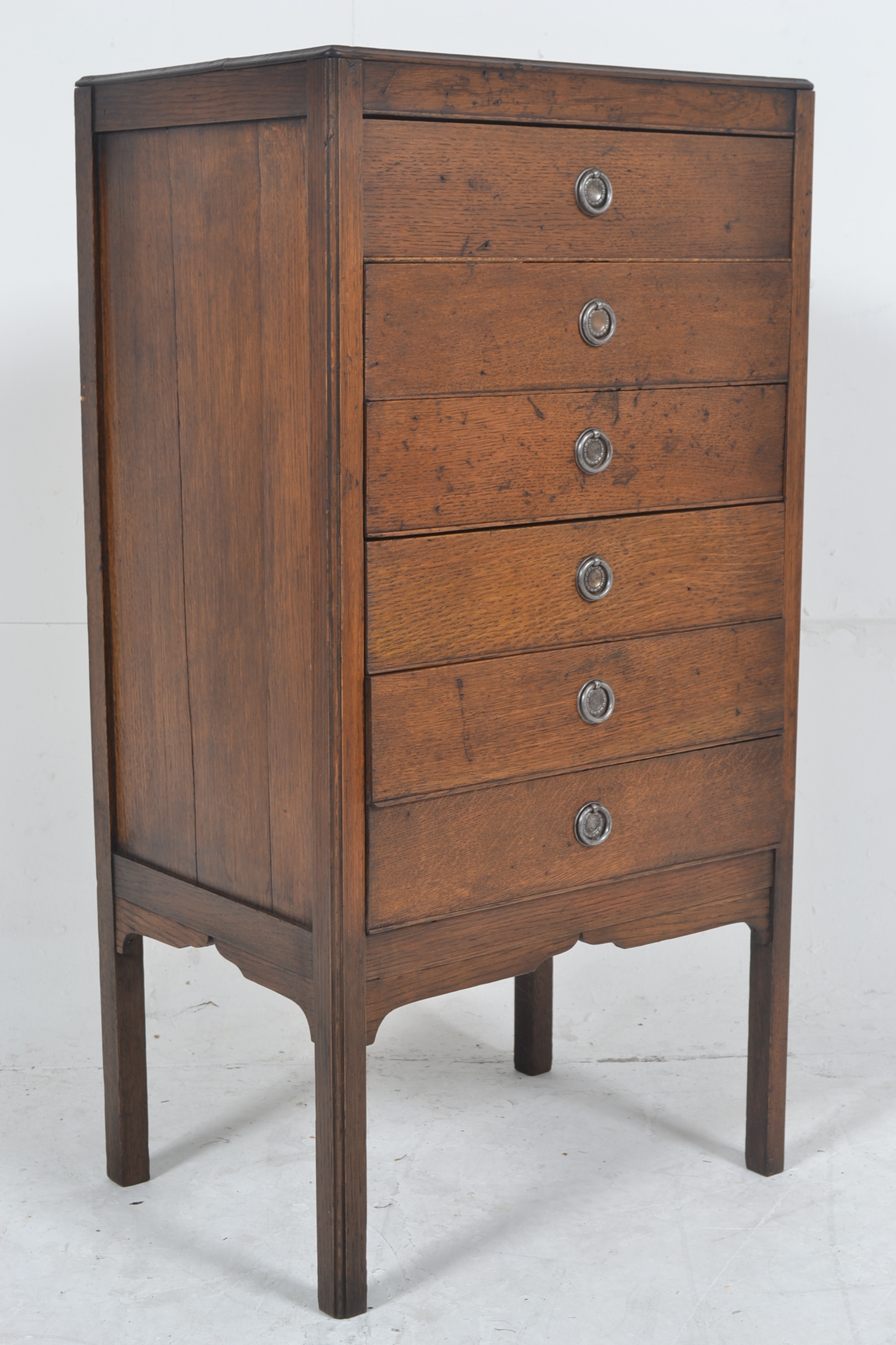 A 1930's upright oak music cabinet, having opening and fold down drawers to front all raised on