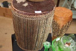 A large skin covered african tribal drum togehter with another