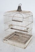 A large early 20th century painted wirework bird cage of square form having set perch within and