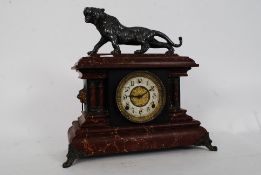 A WML Gilbert Clock Company clock in faux marble finish with a cast metal figure of a lion to top.