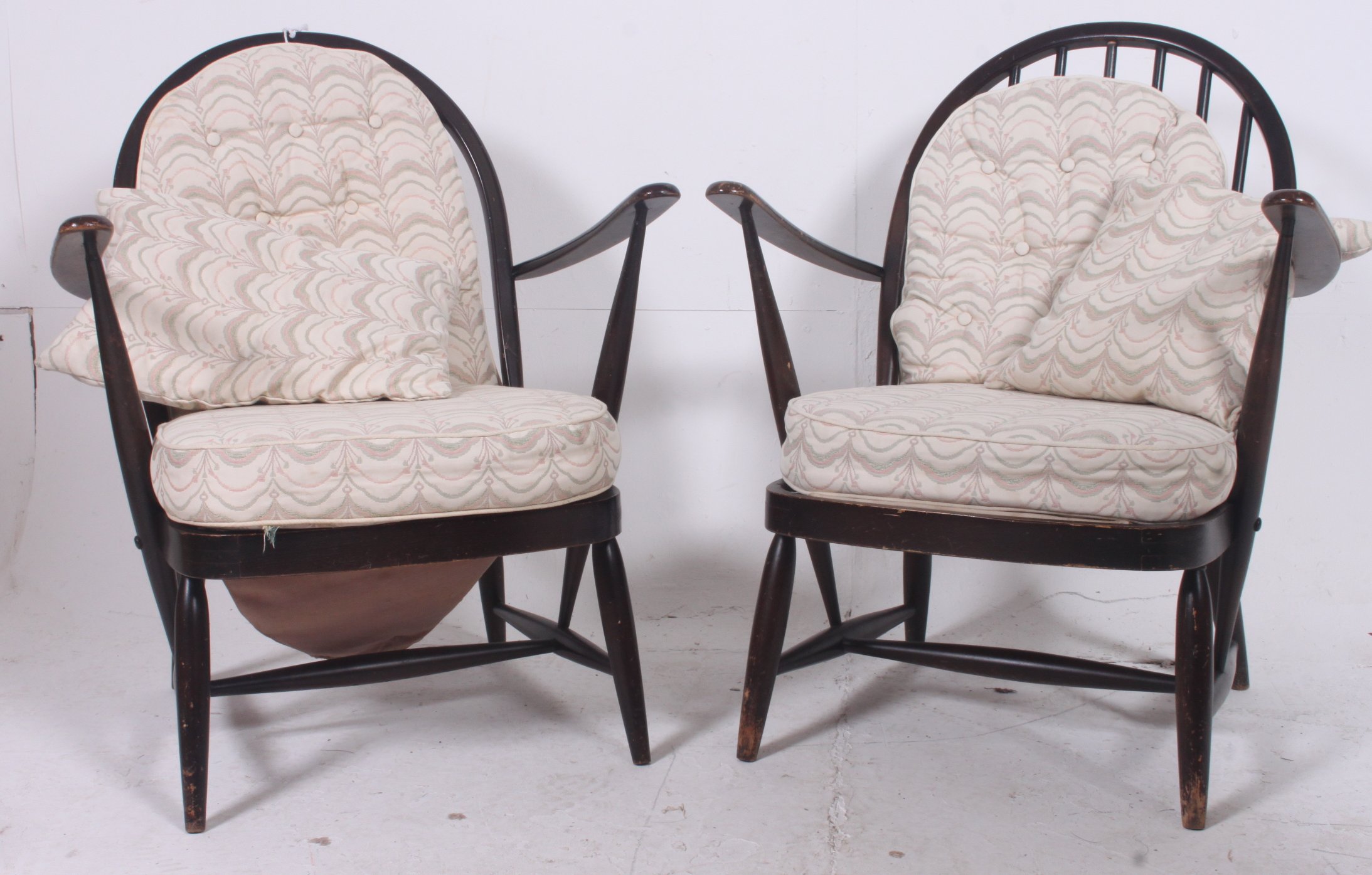 A pair of mid 20th century  Ercol beech wood armchairs being raised on turned legs united by