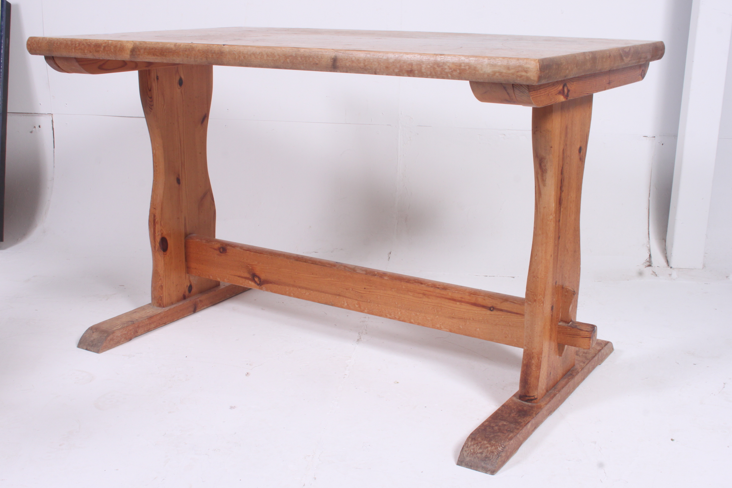 A contemporary pine refectory dining table on shaped supports united by stretcher. 74cm x 121cm x