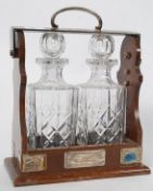 A good mahogany and silver plaque cut glass twin decanter tantalus bearing hallmarked silver