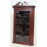 A 19th century Georgian solid mahogany hanging corner display cabinet having shelved interior with