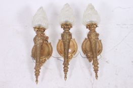 A collection of three 20th century flame wall lights, by Arnold Montrose. Glass shades to top. 63