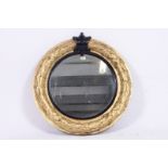 A large 19th century Regency circular mirror having swag detail to the gilded wooden frame with