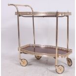 A vintage / retro brass and laquered wood effect tea trolley having large wheels with twin gallery
