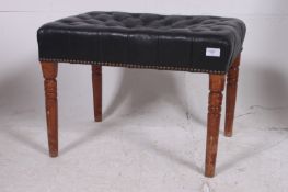 A 20th century black leather button backed chesterfield piano stool being raised on tapered and