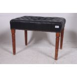 A 20th century black leather button backed chesterfield piano stool being raised on tapered and