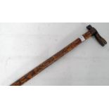 A good tribal walking stick with carved inlaid twin wood detailing having bone teeth alligator