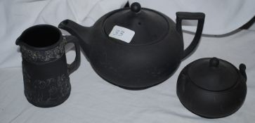 A black porcelain teapot with caddy and milk jug