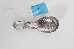 A tested silver caddy spoon having leaf decoration to the bowl with partially illegible monogram to