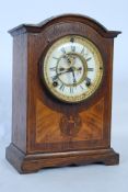 An Edwardian oak inlaid mantle clock having an exposed deabeat escapement to the face having twin