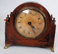 An inlaid mahogany mantel clock with brass finials and feet