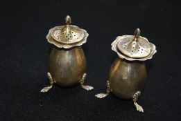 A pair of early 20th century hallmarked silver condiments raised on rococo feet having marks for