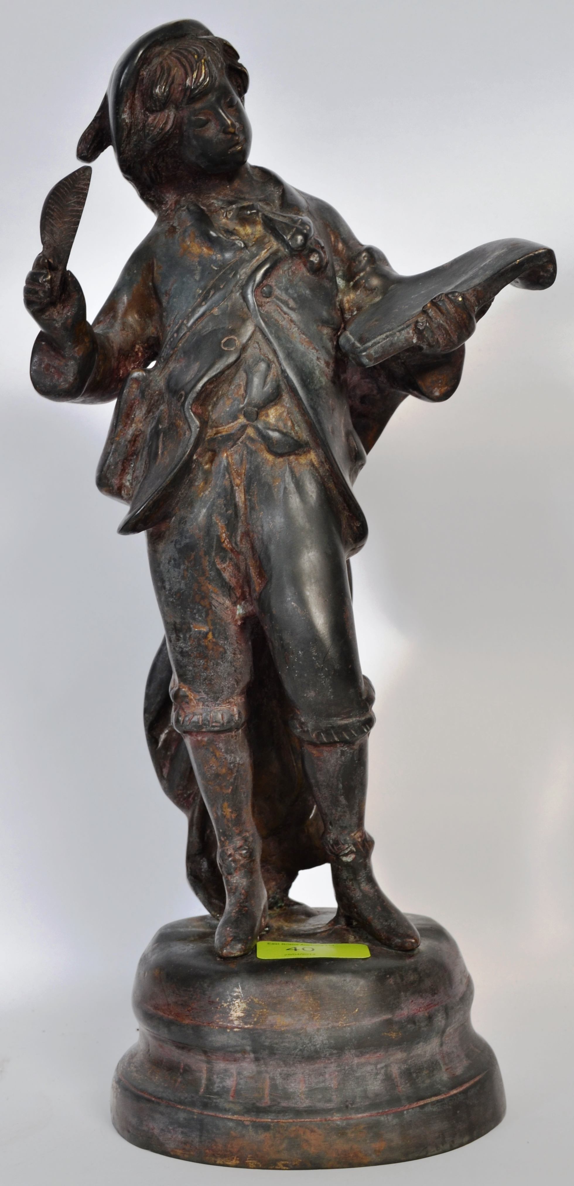 A bronze figure of a boy scholer, with quill and ledger.